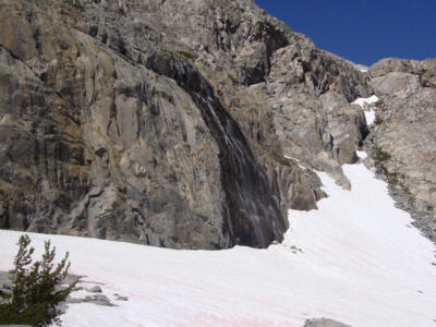 Waterfall dropping draining beneath a snow bank