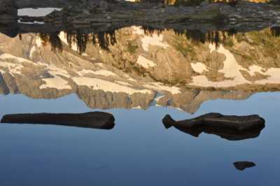 First sunrise on Banner Peak over a tarn near camp