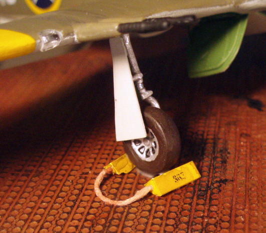 One of those little details - I made wheel chocks out of square plastic stock, joined them with a bit of string tinted brown, and added stenciled-looking decals with the plane's number on them.