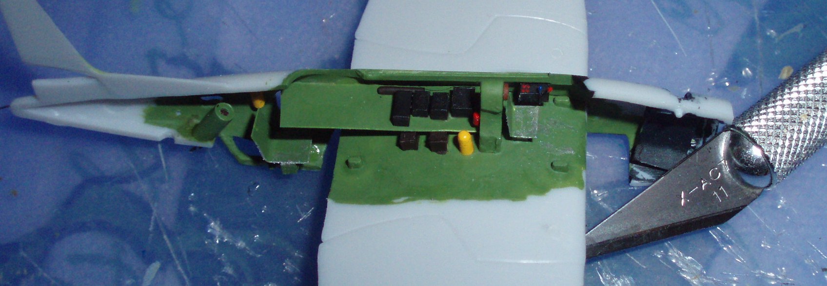 View of the left side Avenger cockpit detail with an Xacto knife blade for scale, showing, from right, cockpit details, rollover pylon, radio gear, and seat and some miscellaneous gear for the radio man.